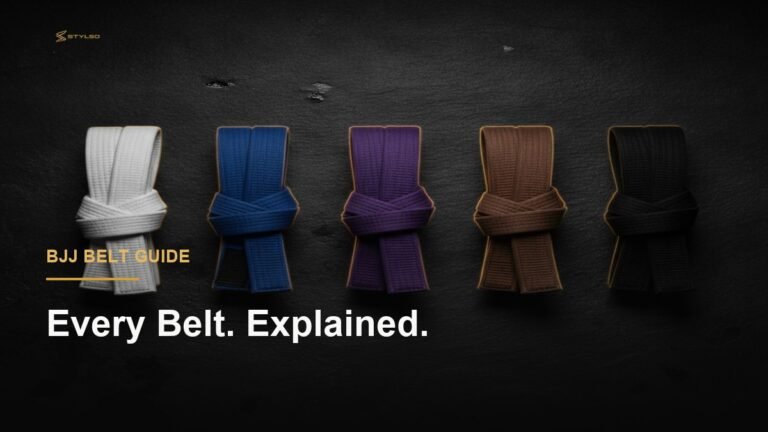Five BJJ belt colours white to black laid on dark slate — Stylso belt ranking guide